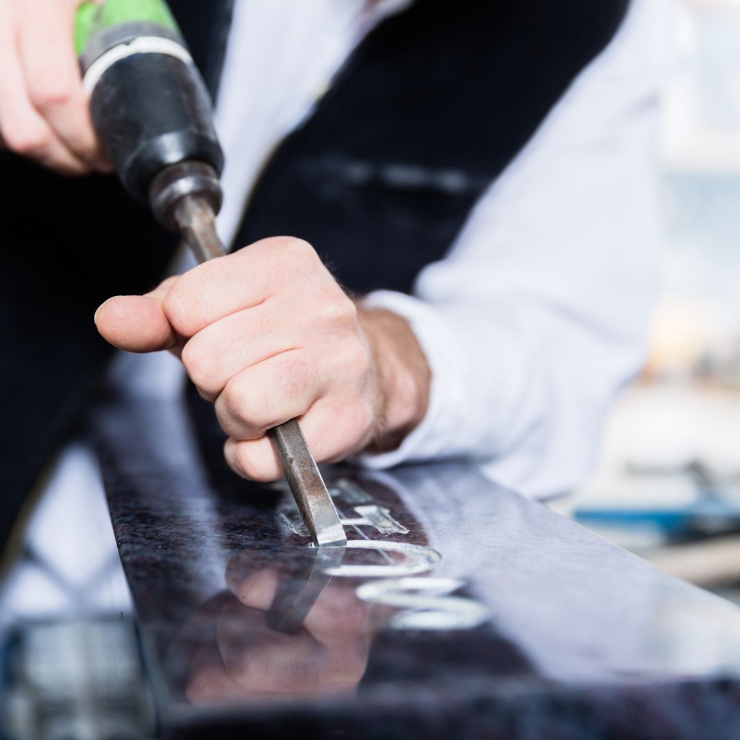 Person inscribing something on a headstone. 