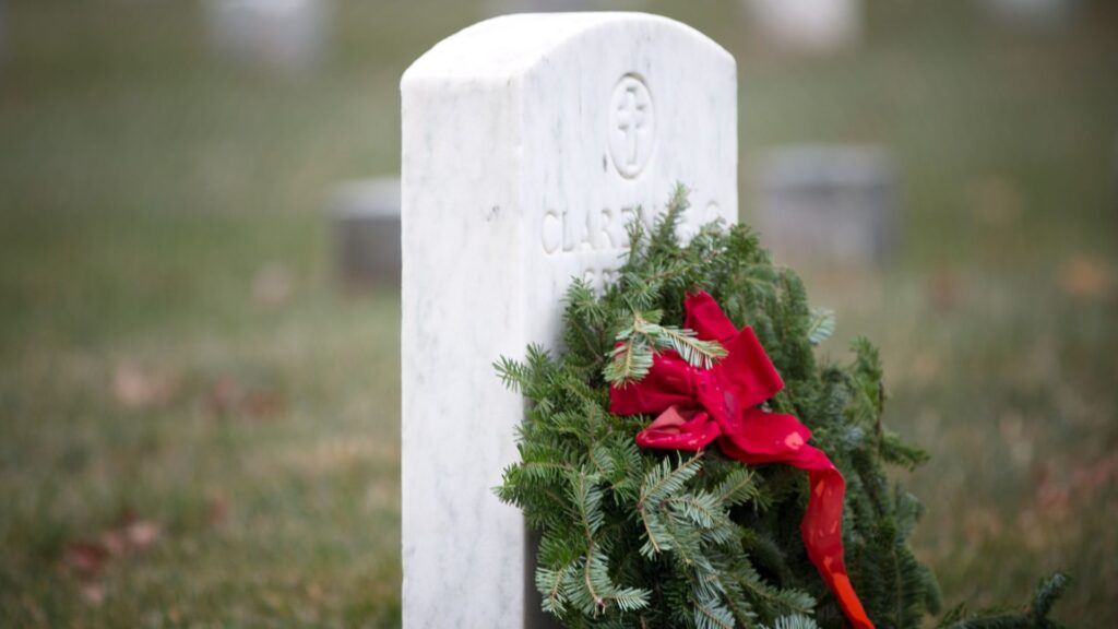 Tombstone with a wreath leaning against it.