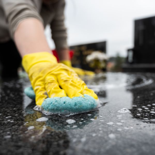 person cleaning a headstone