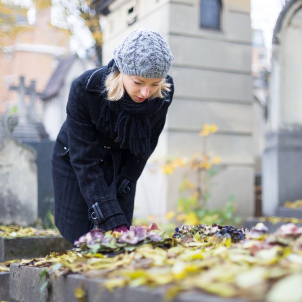 A woman looking at a relatives headstone