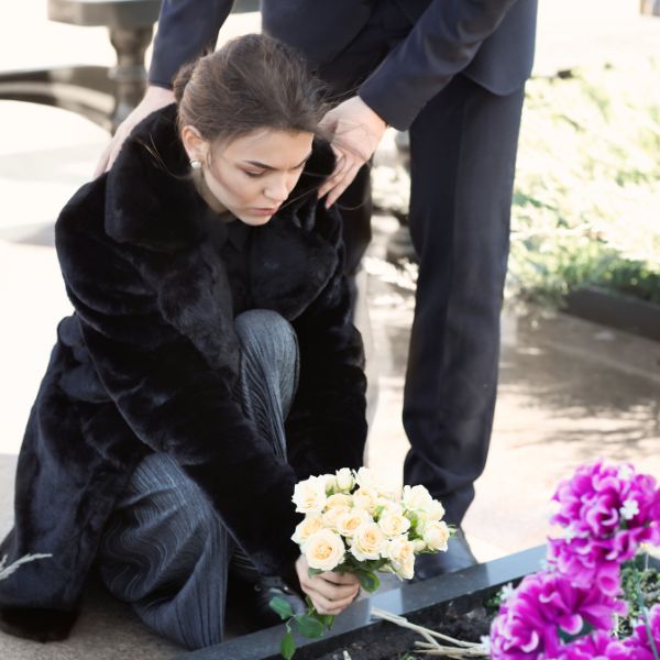 A woman leaving flowers at a loved one's headstone